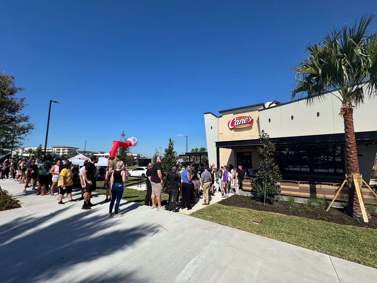 front of raising canes restaurant with line out door